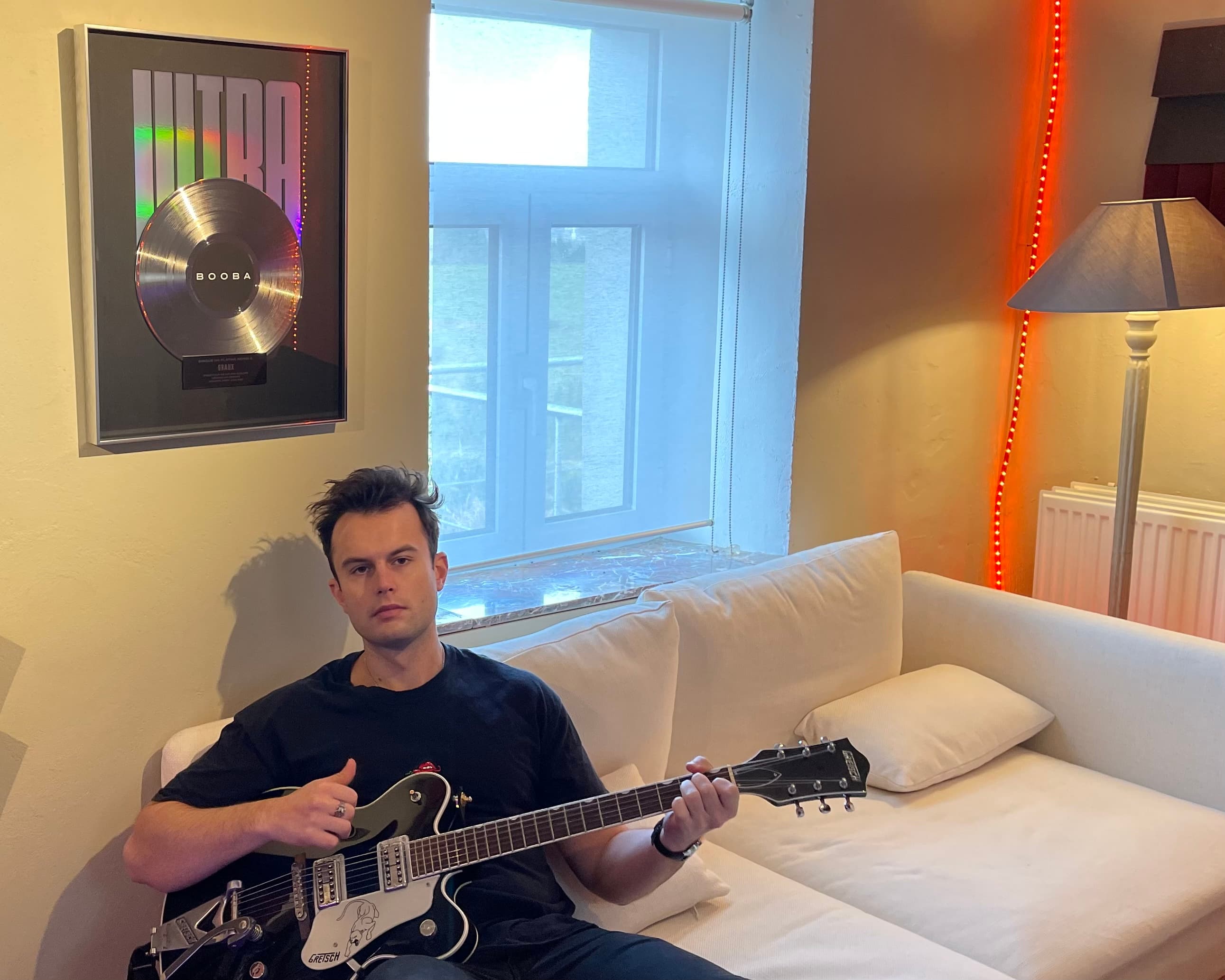 Sébastien Graux in his Brussels studio with a Gretsch guitar in front of the BOOBA — Ultra Platinum Disc plaque