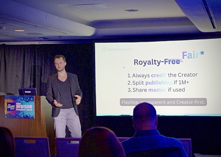 Sébastien Graux on stage at the NAMM Show 2026 in Los Angeles, presenting the Royalty Fair model — Royalty-Free crossed out, replaced with Fair, with the three Royalty Fair principles projected behind him